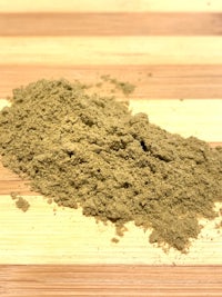 a pile of green powder on a wooden table