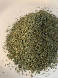 a pile of green herbs on a white plate