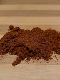 a pile of red chili powder on a wooden table