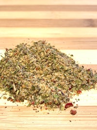 a pile of herbs and spices on a wooden cutting board