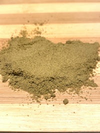 a pile of green powder on top of a wooden cutting board