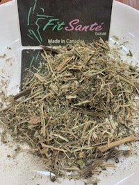 a bowl of dried herbs on a table next to a business card