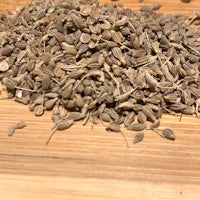 a pile of dried fennel seeds on a wooden table