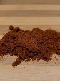 a pile of red chili powder on a wooden table