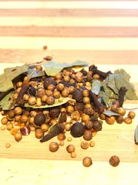 a pile of herbs and spices on a wooden cutting board