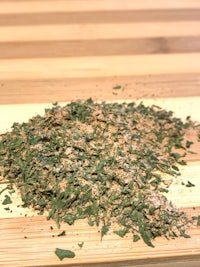 a pile of dried herbs on top of a wooden cutting board