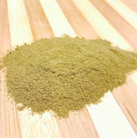 a pile of green powder on a wooden surface