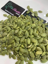 a pile of pumpkin seeds on a white plate