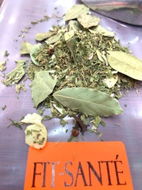 a pile of herbs on a table with a sign that says fit sante